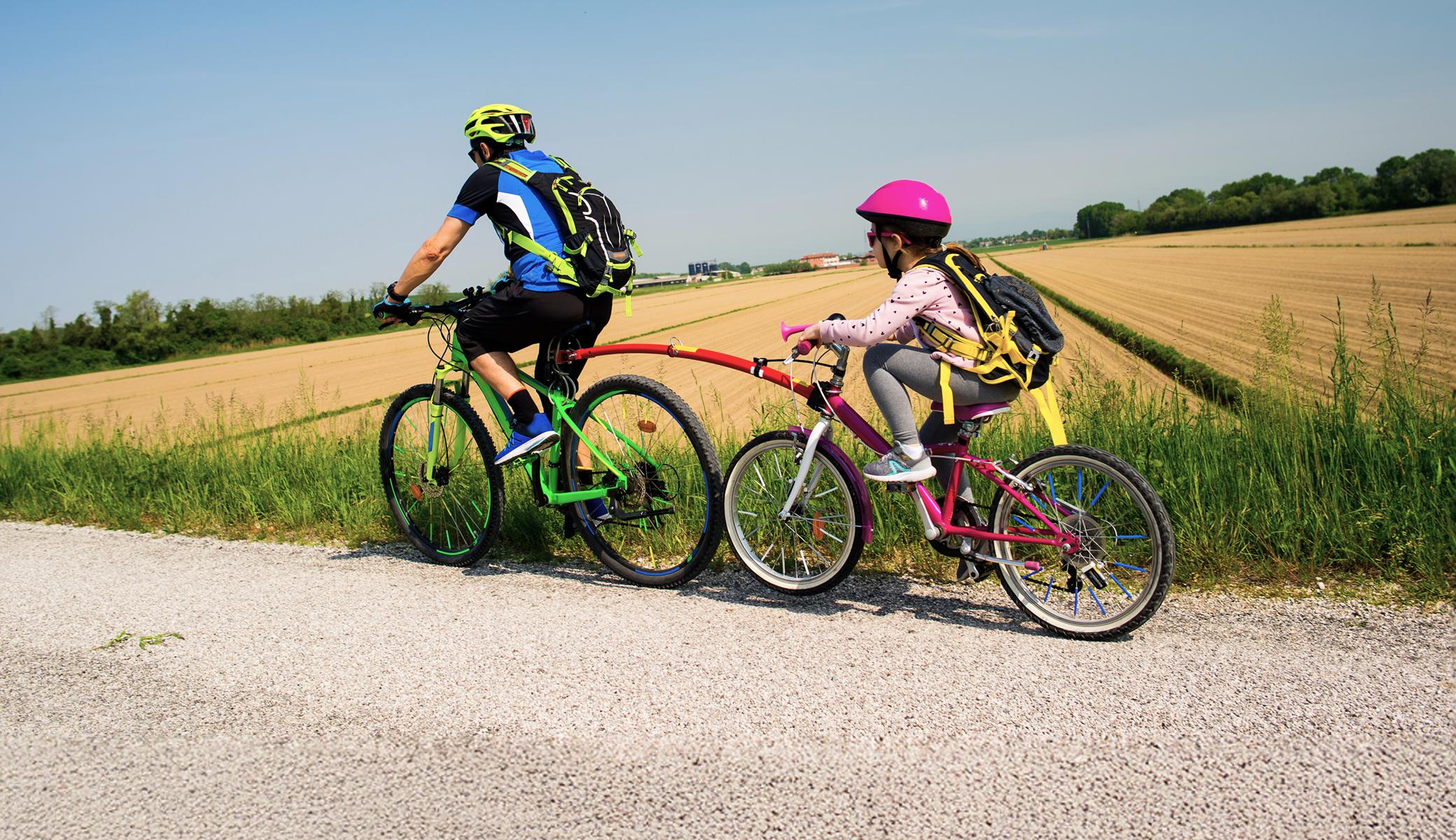 Father and child riding with their bicycles tied together